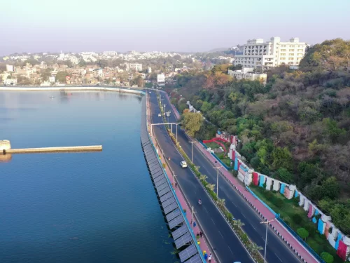 Upper Lake Bhopal aerial view during golden hour, featuring lakeside road hills cityscape solar panels, perfect scenic Madhya Pradesh tour package.