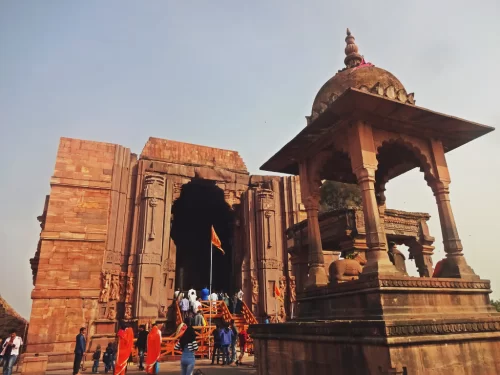 Bhojeshwar Shiva Temple at Bhojpur near Bhopal during clear daylight, featuring red sandstone entrance saffron flag devotees, perfect spiritual Madhya Pradesh tour package.