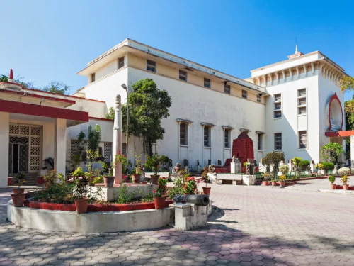 Central Museum Indore Madhya Pradesh in clear daylight, featuring white building with temple tower, gardens and plants, perfect cultural Madhya Pradesh tour package.