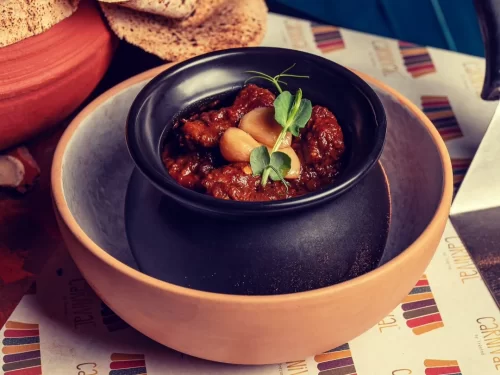 Champaran Meat in slow-cooked spicy onion gravy with garlic garnish, authentic Indian mutton curry, rich Indian cuisine delight.