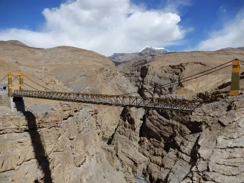 Chicham Bridge near Losar Spiti Valley during partly cloudy skies, featuring Asia's highest suspension bridge spanning deep gorge snow-capped peaks, perfect adventure experience Himachal Pradesh tour package.