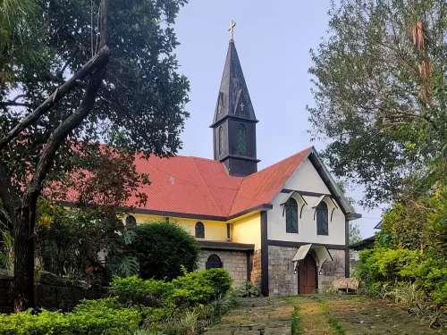 Church of the Epiphany, historic stone church with red roof and Gothic steeple surrounded by greenery