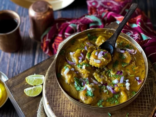 Dal Dhokli in tangy spiced lentil curry with cilantro and onion garnish, authentic Indian one-pot dal dish, steaming hot Indian cuisine delight.