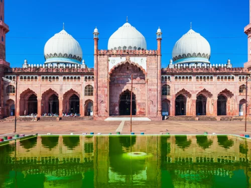 Taj-ul-Masajid at Bhopal during clear daylight, featuring pink sandstone white domes reflecting pool, perfect cultural Madhya Pradesh tour package.