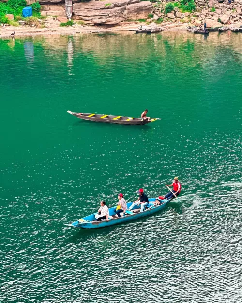 Tourists enjoying boating on the crystal clear Umngot River in Dawki Meghalaya surrounded by scenic hills a popular highlight of Meghalaya tour packages