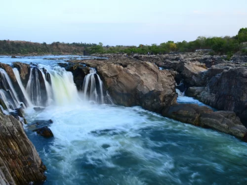 Dhuandhar Falls at Bhedaghat Jabalpur during sunset twilight, featuring Narmada River cascades through marble gorges and lush banks, perfect adventure experience in Madhya Pradesh tour package.