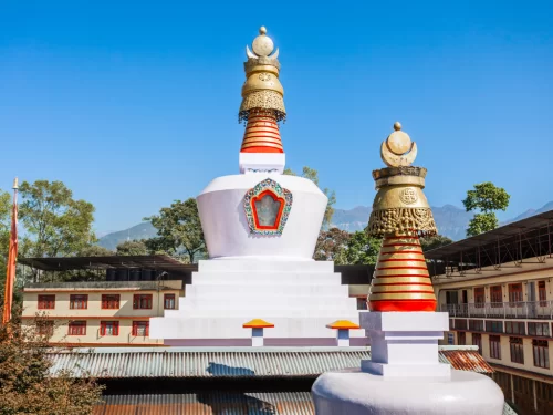 White Do Drul Chorten stupa in Gangtok during sunny daytime, featuring golden spires and blue sky backdrop, perfect spiritual Sikkim tour package