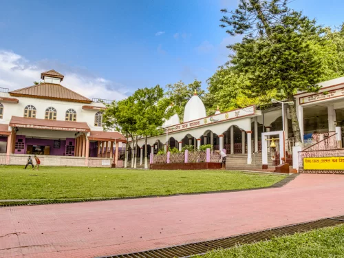 Devotees at Doul Govinda Temple in North Guwahati during clear daytime, featuring temple courtyard, green lawn and walkways, perfect spiritual experience Assam tour package. 