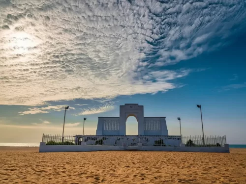 Edward Elliot's Beach in Besant Nagar featuring the Karl Schmidt Memorial on a sandy shoreline with blue waves.