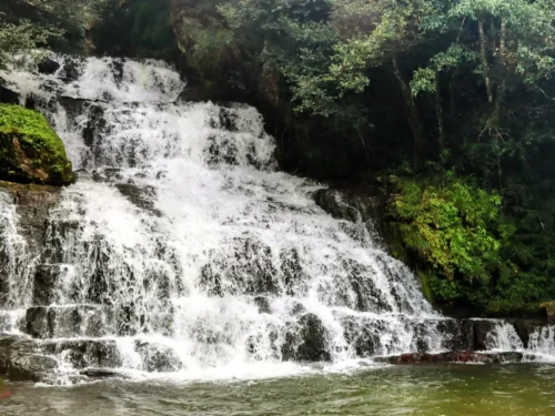 Elephant Falls Shillong Meghalaya multi tier cascading waterfall lush green surroundings rocky base pool white water flow fern covered rocks misty spray, perfect Meghalaya tour packages.