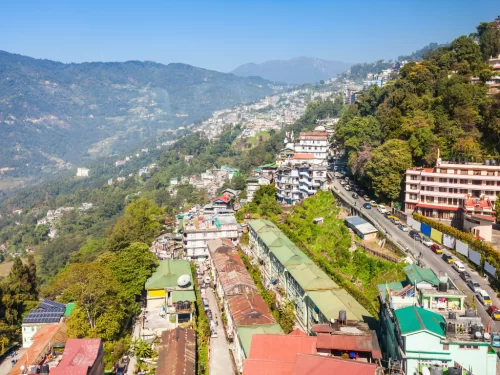 Gangtok valley view from Gangtok Ropeway during clear daylight, featuring terraced houses and forested hills, perfect cityscape Sikkim tour package.