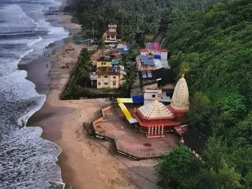 Ganpatipule Beach in Maharashtra featuring the famous seaside Ganpati temple beside the sandy shoreline and lush green hills, a popular coastal destination included in Maharashtra tour packages