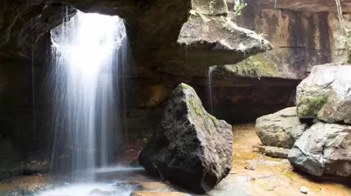 Garden of Caves in Meghalaya, serene waterfall flowing inside a rocky cave formation.