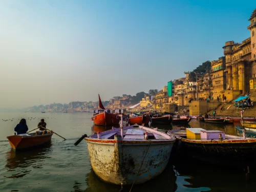 Boat ride at Dashashwamedh Ghat Varanasi during misty sunrise, featuring colorful boats ghats reflections, perfect spiritual Uttar Pradesh tour package.