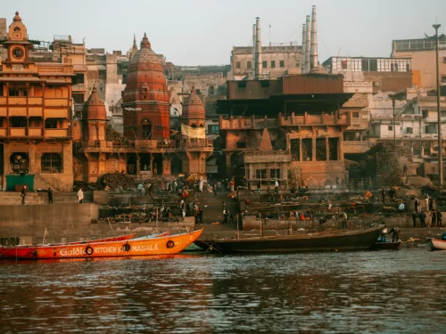 Boat ride at Manikarnika Ghat Varanasi during dusk, featuring temples minarets river reflections, perfect spiritual Uttar Pradesh tour package.