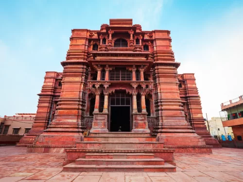 Govind Dev Ji Temple facade at Jaipur during clear daytime, featuring red sandstone architecture, intricate carvings, arched entrance, perfect spiritual experience with Rajasthan Jaipur tour package.
