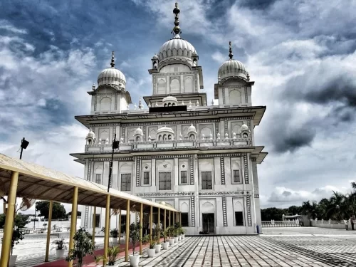 Gurudwara Data Bandi Chhod Sahib in Gwalior featuring white marble domes and a spacious courtyard under dramatic clouds, a revered Sikh pilgrimage site included in Madhya Pradesh tour packages