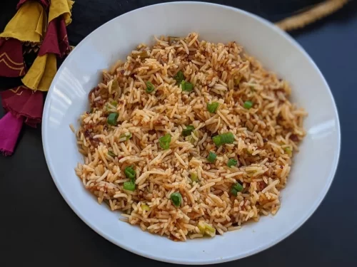 Gyapa Khazi in smoky spiced fried rice with scallion garnish, authentic Indian-style rice dish, steaming hot Indian cuisine delight.