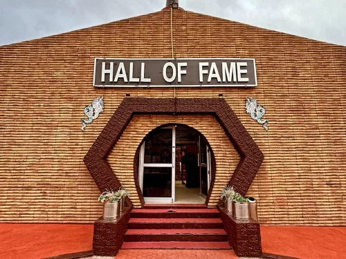 Hall of Fame Leh Ladakh Indian Army museum brick building hexagonal maroon entrance dragon motifs signboard potted plants red carpet steps cloudy sky military war memorial.