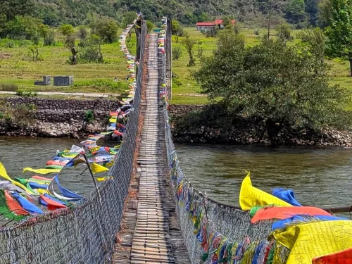Hanging Foot Bridge over river in Arunachal Pradesh with colorful prayer flags and scenic valley backdrop