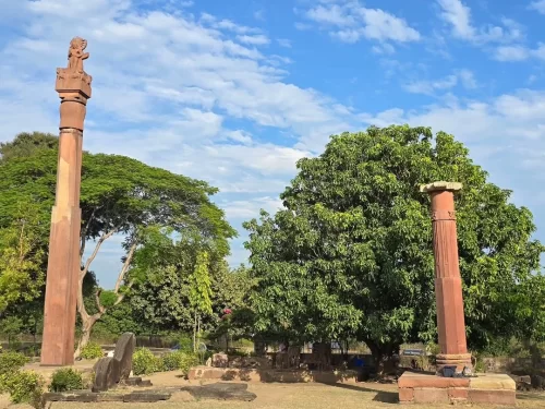 Heliodorus Pillar in Vidisha, Madhya Pradesh standing in an open archaeological site with ancient stone column carvings, featured in Madhya Pradesh tour packages