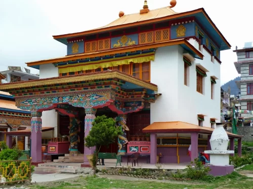 Himalayan Nyingmapa Buddhist Monastery in Manali featuring colorful Tibetan architecture with ornate pillars, golden rooftop details, and prayer wheels.