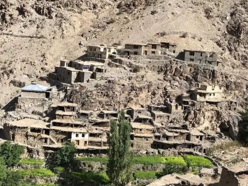 Hunderman Village Kargil Ladakh terraced stone houses cascading down rugged mountainside, Brokpa ghost settlement with poplar trees and green patches amid barren Karakoram landscape, perfect LoC adventure India tour package.