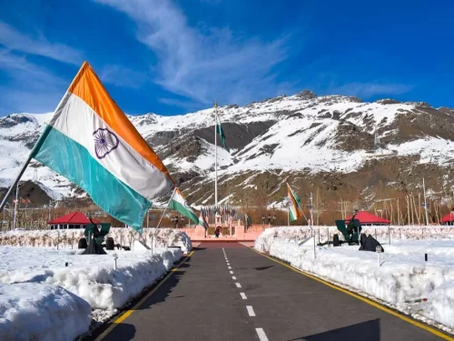 Drass War Memorial Ladakh Indian flags fluttering snowy mountains pink pavilions cannons pathway blue sky Kargil War heroes Operation Vijay tribute, perfect Ladakh heritage tour package.