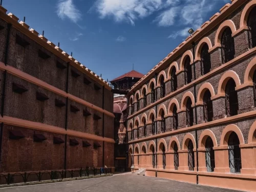 Cell blocks at Cellular Jail Port Blair Andaman during clear skies, featuring brick arches, iron grills, central watchtower, perfect heritage experience Andaman tour package. 