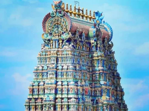 Meenakshi Amman Temple Madurai Tamil Nadu stunning vertical view of ornate multi-tiered gopuram with golden vimana intricate rainbow deity carvings mythical birds under clear blue sky, legendary Dravidian Hindu temple tower architectural splendor heritage