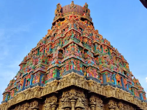 Upward perspective of vibrantly sculpted five-tiered Rajagopuram Arulmigu Koodal Azhagar Temple Madurai Tamil Nadu with intricate Dravidian stucco deities detailed stone base against clear blue sky, ideal for Madurai temple architecture photography