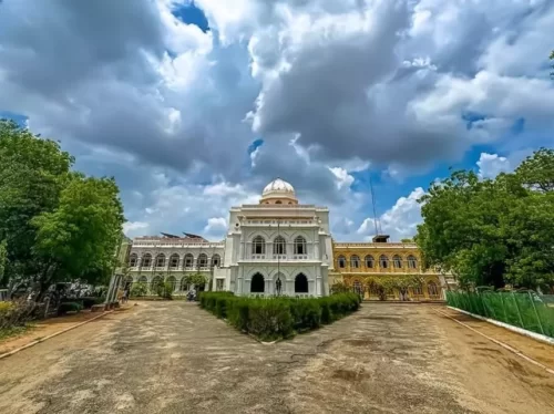 Gandhi Memorial Museum Madurai Tamil Nadu majestic white Indo-Saracenic architecture building with dome arches surrounded by trees under blue sky with clouds, historic freedom struggle tour package.