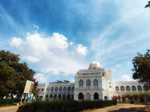 Gandhi Memorial Museum Madurai Tamil Nadu grand white colonial architecture with dome and arched windows surrounded by greenery under blue sky with scattered clouds, inspiring independence history tour package.