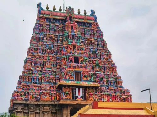 Towering seven-tiered Rajagopuram Arulmigu Kallazhagar Sundararaja Perumal Temple Alagar Kovil Madurai Tamil Nadu with vibrant multicolored deity sculptures red roof golden accents granite base cloudy sky lamp post, perfect Madurai temple tour package.