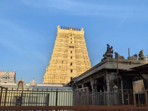 Majestic gopuram of Sri Arulmigu Ramanathaswamy Temple in Rameswaram during blue sky, featuring statues, railings, perfect spiritual Rameswaram tour package.