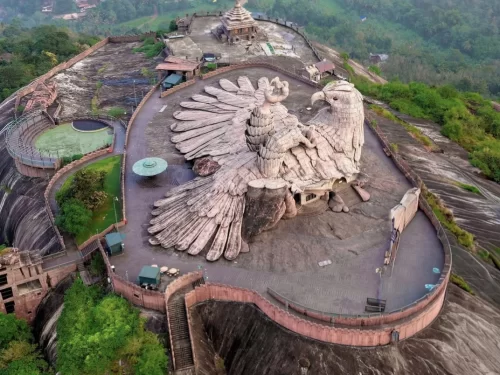 Aerial view colossal Jatayu bird sculpture world's largest at Jatayu Earth's Center Nature Park Chadayamangalam Kollam Kerala, featuring sprawling wings temple amphitheatre pool misty hill backdrop lush greenery, perfect adventure experience Jatayu Ramaya