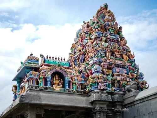 Closeup rainbow-hued multi-tiered gopuram mythical deities Perur Patteeswarar Temple Coimbatore partly cloudy sky, featuring intricate Tamil temple tower stone plinth, perfect vibrant Chola heritage Tamil Nadu tour package