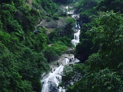 Multi-tiered cascading Siruvani Waterfalls surrounded dense tropical forest rocky cliffs Tamil Nadu Western Ghats lush greenery, stunning nature escape Coimbatore eco-tourism itinerary.