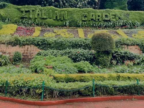 Floral entrance sign of Italian Garden Government Botanical Garden Ooty Udhagamandalam Nilgiris Tamil Nadu India crafted with green shrubs yellow flower letters surrounded by vibrant flower beds hedges terracotta walls lush hillside backdrop, perfect Nilg
