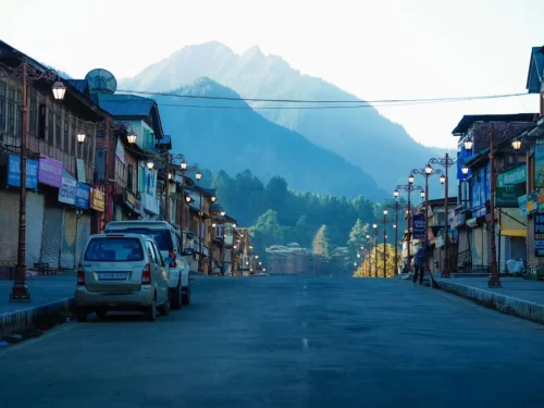 Pahalgam main market street during twilight, featuring vintage lamps & snow peaks backdrop, perfect romantic experience Kashmir tour packages. 