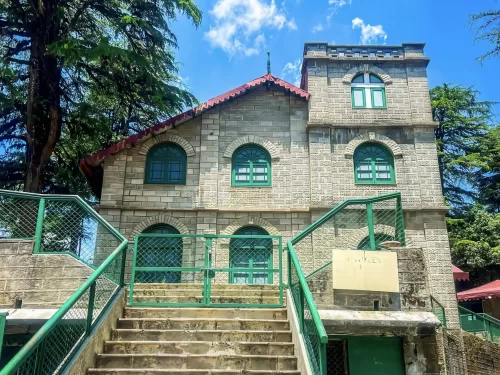 Kellogg Memorial Church at Landour during sunny day, featuring stone facade, green railings, stairs and deodar trees, perfect adventure Uttarakhand tour package.