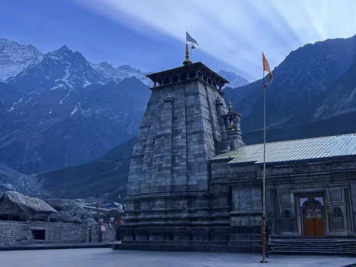 Majestic Kedarnath Temple at Kedarnath during golden hour sunlight, featuring snow peaks saffron flags grey shikharas, perfect spiritual experience Kedarnath Char Dham Yatra tour packages.