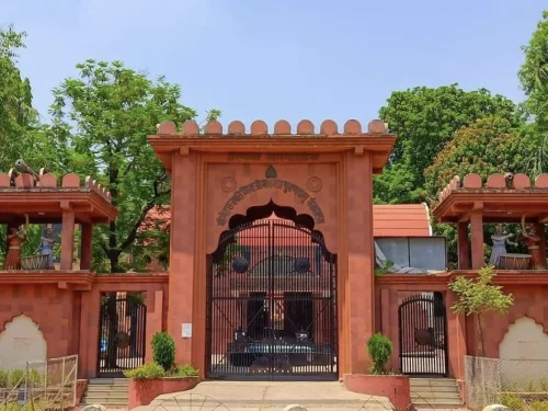Ornate Chhatrapati Shivaji Maharaj Museum Aurangabad Maharashtra grand entrance gate in red sandstone Rajasthani architecture featuring jharokhas monkey statues arched doorway Devanagari inscription flanked by neem trees blue skies, perfect Chhatrapati Sa