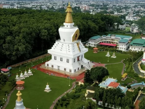 Tibetan stupa at Mindrolling Monastery Clement Town during sunny day, featuring white-gold tower surrounded by green lawns and Dehradun cityscape, perfect spiritual experience Uttarakhand tour package.