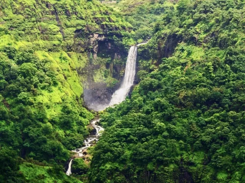 Towering Kune Falls plunging through lush green rainforest valley at Kune Khandala Lonavala Maharashtra, featuring misty cliffs cascading tiers Sahyadri hills monsoon mist, perfect waterfall experience Lonavala Khandala monsoon waterfall trek package. 