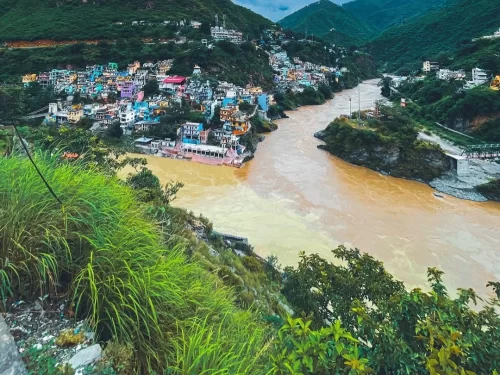 Devprayag Uttarakhand colorful hillside village blue pink houses brown muddy Alaknanda River ghats green grass hills mountains misty, perfect Uttarakhand tour packages.
