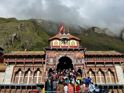 Badrinath Temple Uttarakhand vibrant red gold facade snowy mountains blue sky large pilgrim crowd Char Dham Yatra Uttarakhand tour packages.