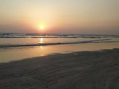 Golden sunset at Varsoli Beach in Alibaug, featuring calm waves and sandy shore reflections, perfect Alibaug tour package