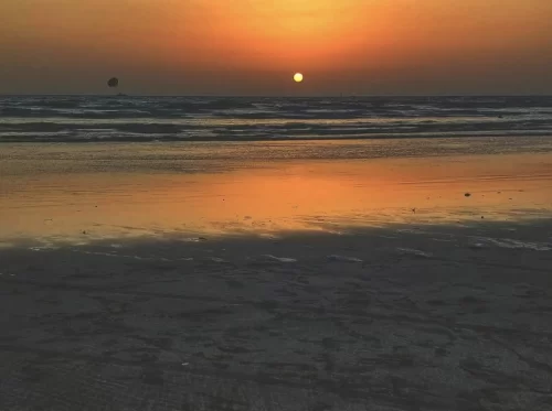 Nagaon Beach Alibaug Maharashtra spectacular orange sunset over Arabian Sea with kitesurfer silhouette glowing waves and sandy shore, premier water sports destination in Raigad Alibaug beach holiday p