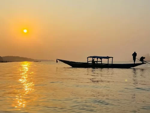 Chilika Lake Odisha traditional thatched boat silhouette sunrise golden hour fisherman serene waters, perfect Puri birdwatching dolphin safari tour package.